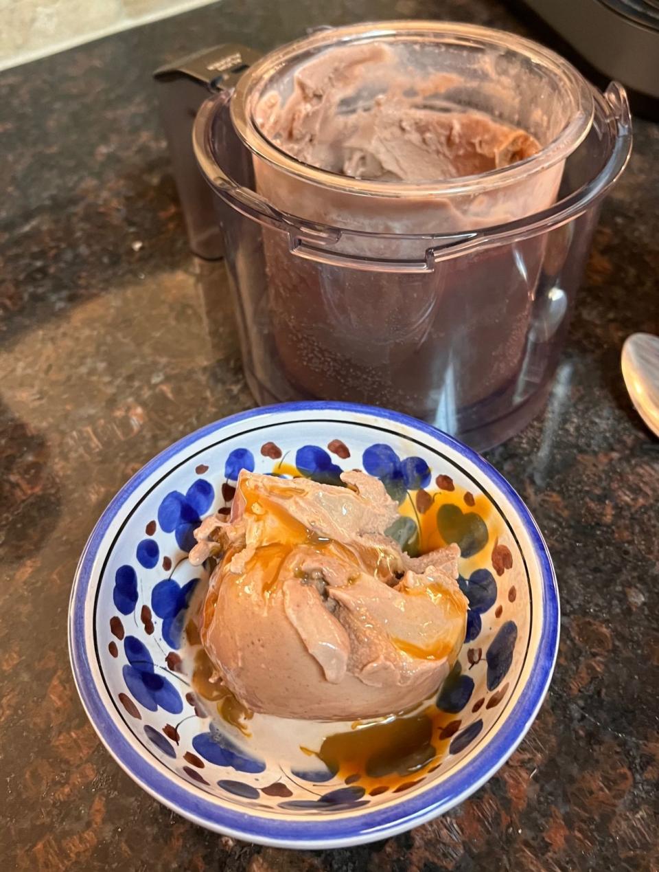 A hand-painted ceramic bowl of chocolate ice cream on a kitchen counter next to the Ninja Creami.