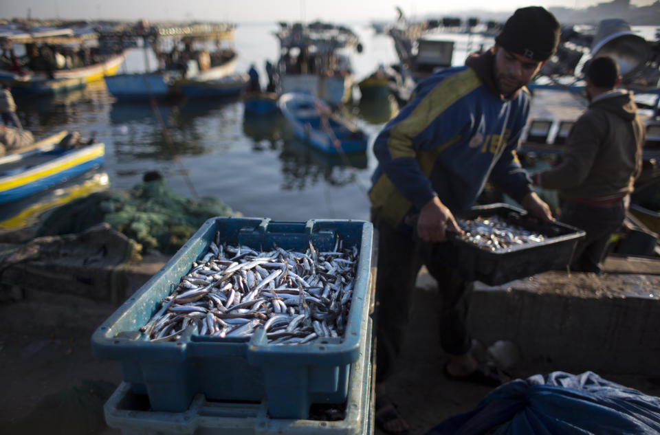 FILE - In this April 3, 2019, file photo, Palestinian fishermen unload their catch after a night fishing trip, in the Gaza Seaport. The Israeli military says it’s scaling back the permitted fishing zone off the Mediterranean coast of Gaza following a rocket attack from the strip the previous day. The military said Tuesday, April 30, 2019 that fishing would only be permitted up to 6 nautical miles — about 11 kilometers — until further notice. (AP Photo/Khalil Hamra, File)