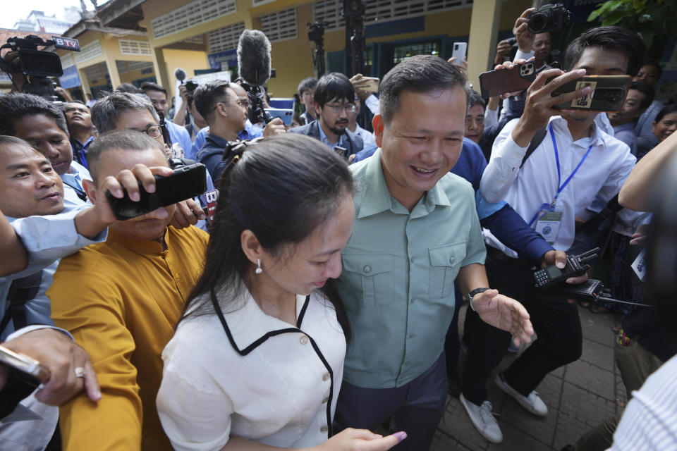 Hun Manet, center, of the Cambodian People's Party (CPP), son of Cambodia Prime Minister Hun Sen, also army chief, walks outside a polling station together with his wife, Pich Chanmony, front left, before voting at a polling station in Phnom Penh, Cambodia, Sunday, July 23, 2023. Hun Sen has suggested he will hand off the premiership during the upcoming five-year term to his oldest son, Hun Manet, perhaps as early as the first month after the elections. (AP Photo/Heng Sinith)
