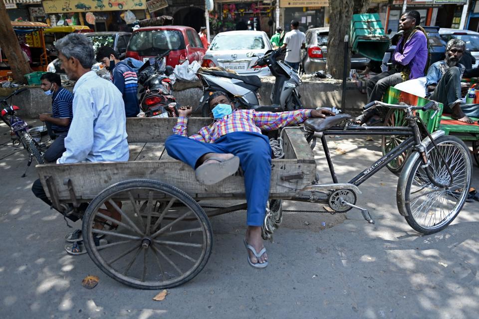 Rickshaw drivers rest along a street in the old quarters of New Delhi on April 19, 2021, as India's capital will impose a week-long lockdown from tonight, officials said, while the megacity struggles to contain a huge surge in Covid-19 cases with hospitals running out of beds and oxygen supplies low. (Photo by Sajjad HUSSAIN / AFP) (Photo by SAJJAD HUSSAIN/AFP via Getty Images)