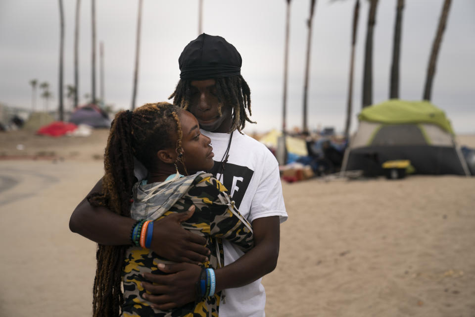 Yahto Bank and his girlfriend, Nas, a couple living in an homeless encampment set up along the Venice Beach boardwalk, embrace each other while waiting to pick up free meals in the Venice neighborhood of Los Angeles, Tuesday, June 29, 2021. (AP Photo/Jae C. Hong)