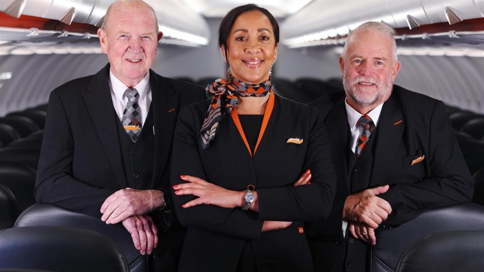 Three cabin crew staff pose on an easyJet airplane.