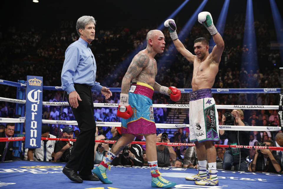 England's Amir Khan, right, raises his arms in victory at the end of his silver welterweight title boxing fight against Luis Collazo, center, Saturday, May 3, 2014, in Las Vegas. Referee Vic Drakulich is at left. Khan won the bout by unanimous decision. (AP Photo/Isaac Brekken)