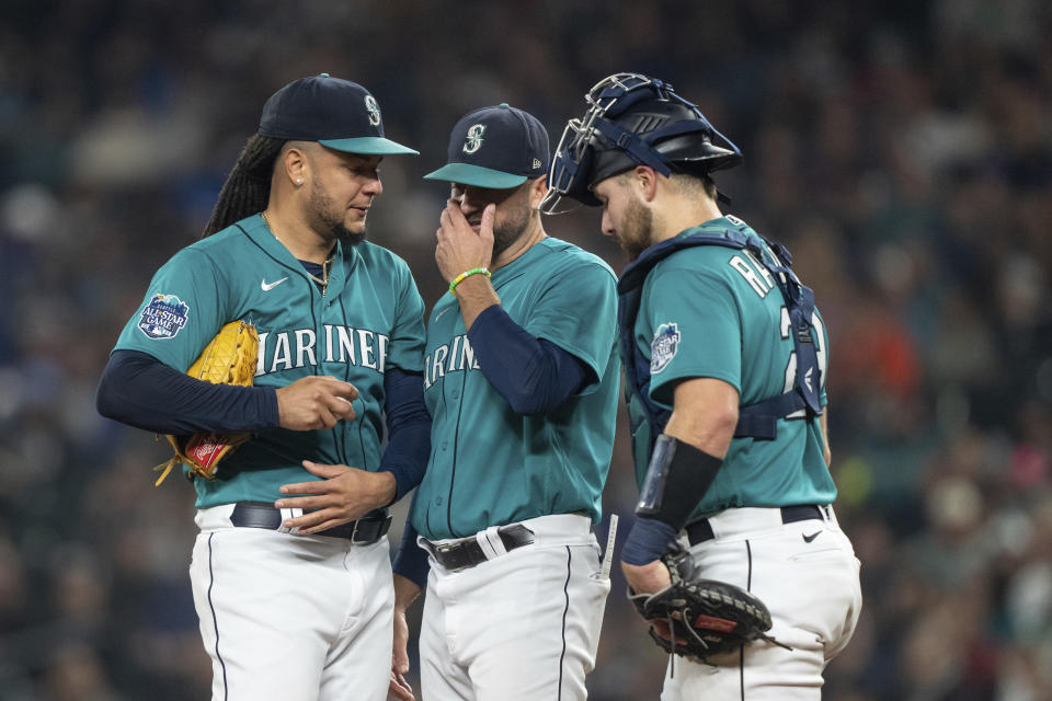 Seattle Mariners starting pitcher Luis Castillo, left, meets at the mound with pitching coach Pete Woodworth, middle, and catcher Cal Raleigh during the second inning of a baseball game against the Houston Astros, Monday, Sept. 25, 2023, in Seattle. (AP Photo/Stephen Brashear)