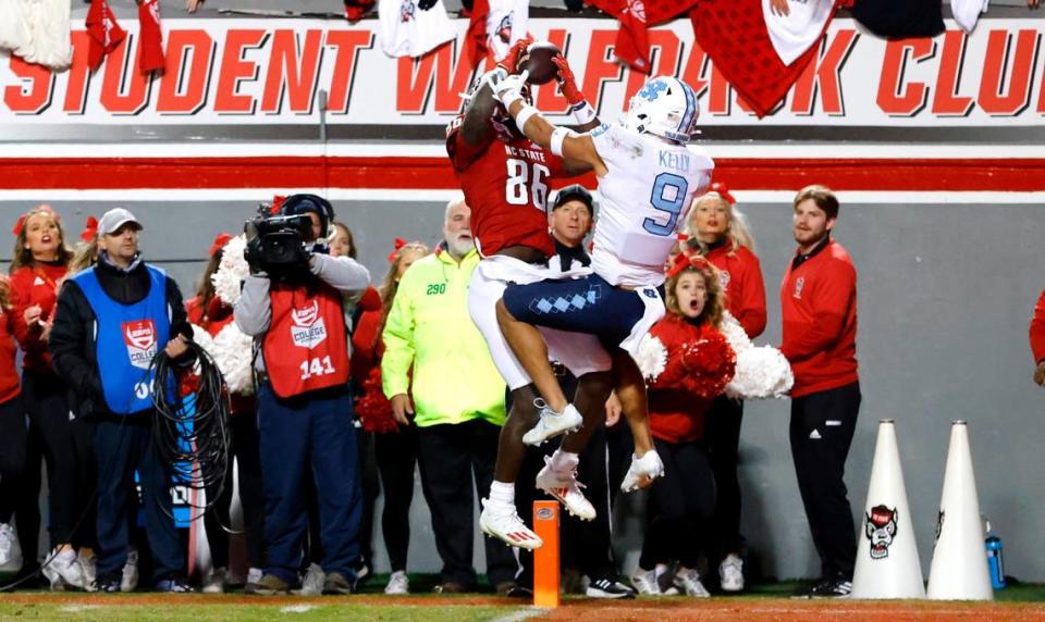 N.C. State wide receiver Emeka Emezie (86) makes what would be the game winning touchdown reception as North Carolina defensive back Cam’Ron Kelly (9) defends late in the second half of N.C. State’s 34-30 victory over UNC at Carter-Finley Stadium in Raleigh, N.C., Friday, November 26, 2021.