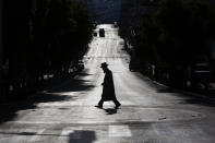 An ultra-Orthodox Jew crosses a mainly deserted street because of the government's measures to help stop the spread of the coronavirus, in Bnei Brak, Israel, Wednesday, April 8, 2020. Israeli Prime Minister Benjamin Netanyahu announced Monday a complete lockdown over the upcoming Passover feast to control the country's coronavirus outbreak, but offered citizens some hope by saying he expects to lift widespread restrictions after the week-long Jewish holiday. (AP Photo/Oded Balilty)