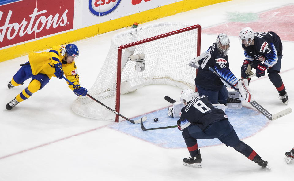 Sweden's Albin Sundsvik (29) tries to knock in the loose puck as U.S. goalie Spencer Knight (30) makes the stop and Jake Sanderson (8) and John Farinacci (25) defend during the second period of an IIHF World Junior Hockey Championship game Thursday, Dec. 31, 2020, in Edmonton, Alberta. (Jason Franson/The Canadian Press via AP)