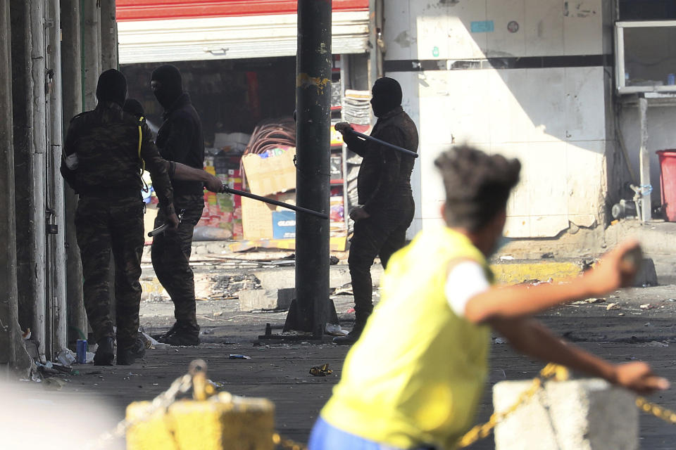 An anti-government protester prepares to throw a stone at security forces during ongoing protests in central Baghdad, Iraq, Saturday, Nov. 9, 2019. (AP Photo/Hadi Mizban)