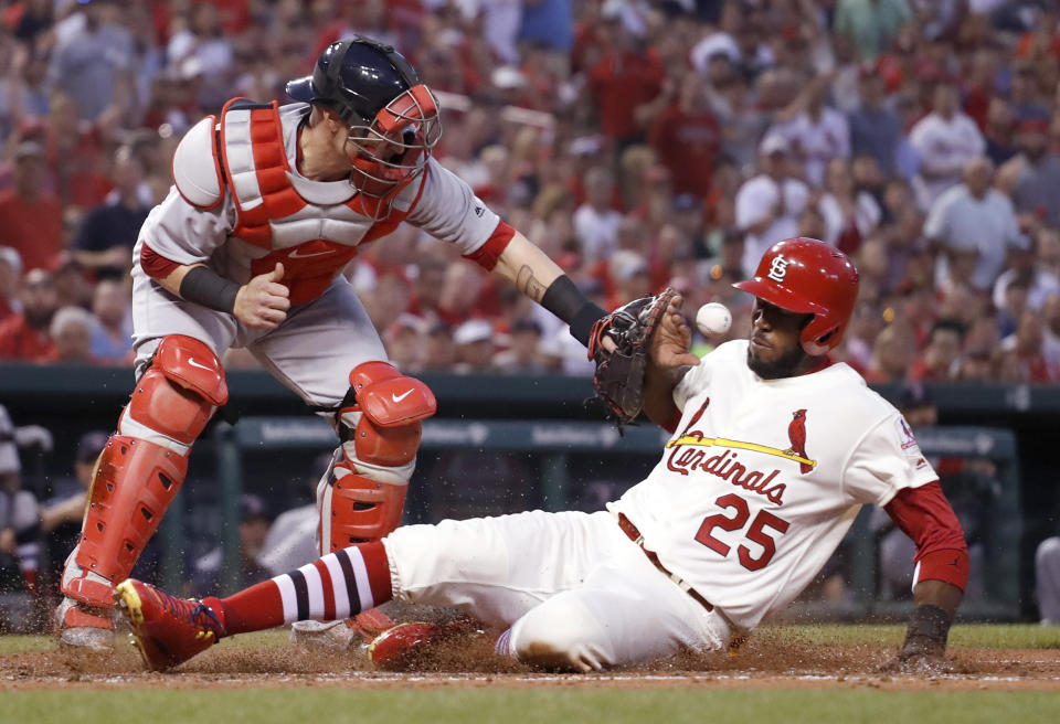 FILE - In this May 16, 2017, file photo, St. Louis Cardinals' Dexter Fowler (25) scores as Boston Red Sox catcher Christian Vazquez is unable to catch the ball during the third inning of a baseball game in St. Louis. Most of the games played between the Red Sox and Cardinals have been in the World Series. If not for the coronavirus pandemic, they would have been playing a regular-season series next weekend at Fenway Park. (AP Photo/Jeff Roberson, File)