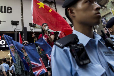 Pro-China demonstrator Anna Chan (C) waves a Chinese flag as another tears a former Hong Kong colonial flag at Mongkok shopping district in Hong Kong, China July 11, 2015. Picture taken July 11, 2015. REUTERS/Tyrone Siu