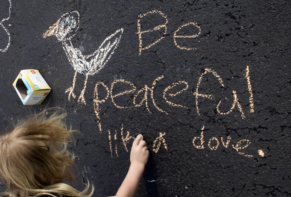 FILE - In this Wednesday, March 8, 2020 file photo, Amber Dodd, 7, makes chalk art with uplifting messages on her driveway in Salem, Va. Residents have have been making chalk drawings on their driveways to connect with one another. (Heather Rousseau/The Roanoke Times via AP)