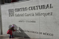 A girl touches the sign outside the Gabriel Garcia Marquez cultural center in downtown Bogota, Colombia, Thursday, April 17, 2014. The Colombian Nobel laureate Gabriel Garcia Marquez died in Mexico City on Thursday. (AP Photo/Diana Sanchez)