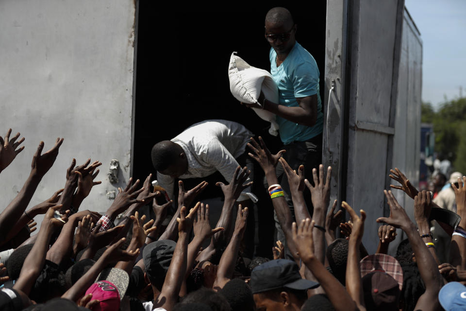 People in need of food call out for a sack of rice during a federal government distribution of food and school supplies to some residents of Cite Soleil, in Port-au-Prince, Haiti, Thursday, Oct. 3, 2019. The daily struggles of Haitians have only become more acute as recent anti-government protests and roadblocks force the closure of businesses, sometimes permanently, as people lose jobs and dwindling incomes fall behind a spike in prices. (AP Photo/Rebecca Blackwell)