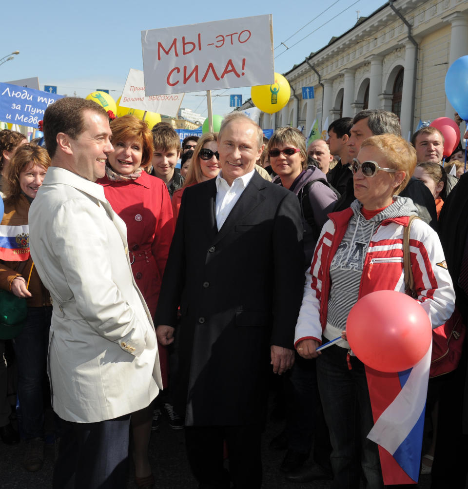 Russian President Dmitry Medvedev, center left, and President-elect, Prime Minister Vladimir Putin, center, talk with demonstrators as they take part in a May Day rally in Moscow, Tuesday, May 1, 2012. Around 100,000 people in Moscow, including President Dmitry Medvedev and President-elect, Prime Minister Vladimir Putin, took part in the main march through the city center. The poster reads: "We are the power". (AP Photo/RIA-Novosti, Alexei Druzhinin, Government Press Service)