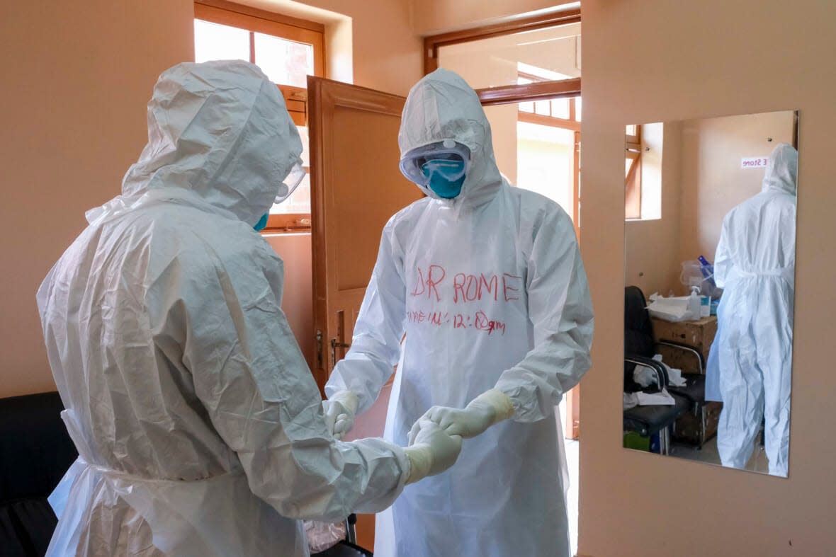 Doctors wearing protective equipment pray together before they visit a patient who was in contact with an Ebola victim, in the isolation section of Entebbe Regional Referral Hospital in Entebbe, Uganda on Oct. 20, 2022. (AP Photo/Hajarah Nalwadda, File)