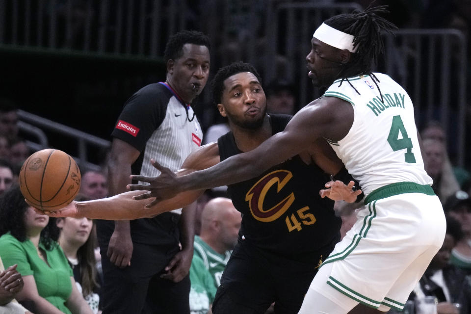 Cleveland Cavaliers guard Donovan Mitchell (45) looks to pass while pressured by Boston Celtics guard Jrue Holiday (4) during the second half of Game 1 of an NBA basketball second-round playoff series Tuesday, May 7, 2024, in Boston. (AP Photo/Charles Krupa)