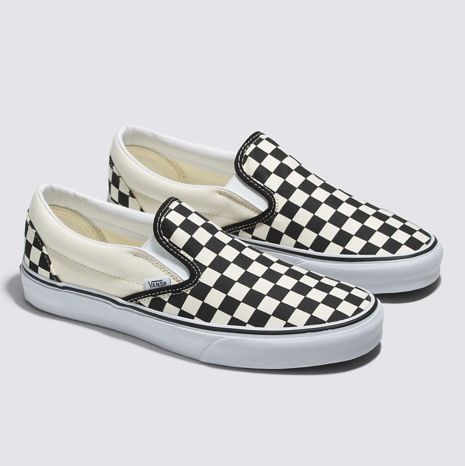 A pair of black and white checkerboard slip-on Vans