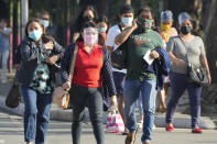 People wearing mask to prevent the spread of the coronavirus walks beside a street in Quezon city, Philippines on Monday, Jan. 17, 2022. People who are not fully vaccinated against COVID-19 were banned from riding public transport in the Philippine capital region Monday in a desperate move that has sparked protests from labor and human rights groups. (AP Photo/Aaron Favila)