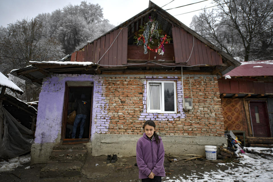 A girl stands in front of her home in Nucsoara, Romania, Saturday, Jan. 9, 2021. Valeriu Nicolae and his team visited villages at the foot of the Carpathian mountains, northwest of Bucharest, to deliver aid. The rights activist has earned praise for his tireless campaign to change for the better the lives of the Balkan country’s poorest and underprivileged residents, particularly the children. (AP Photo/Andreea Alexandru)