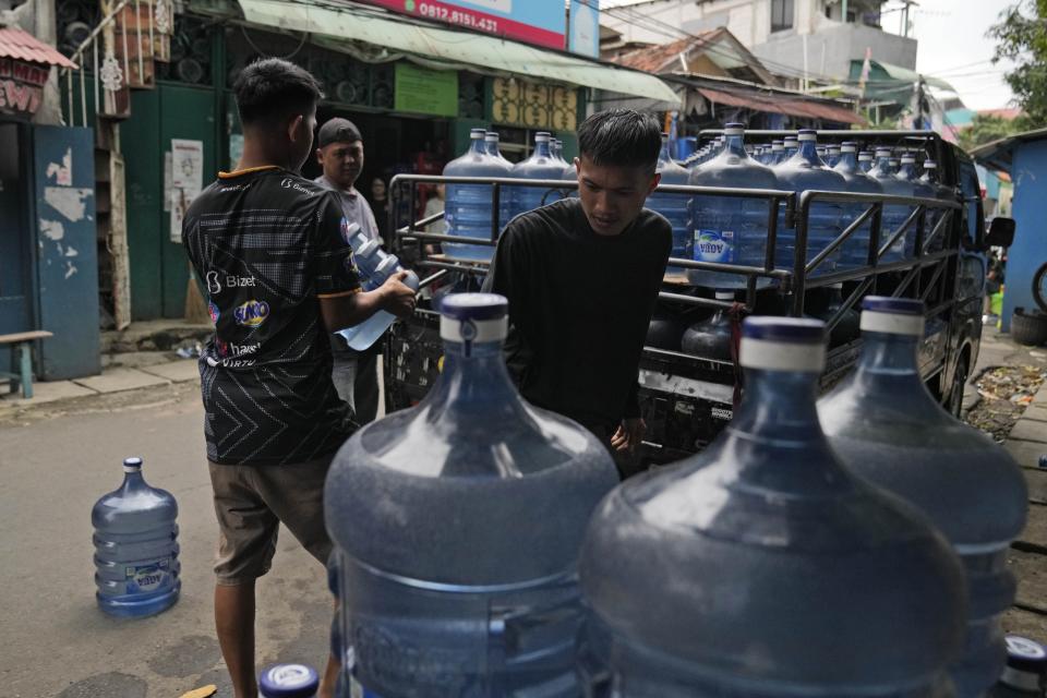 Workers unload bottles of mineral water from the back of a truck in Jakarta, Indonesia, Wednesday, March 13, 2024. Access to clean water is uncertain and millions of Indonesians across the country buy water in large refillable containers or single-use packaged plastic bottles. (AP Photo/Dita Alangkara)