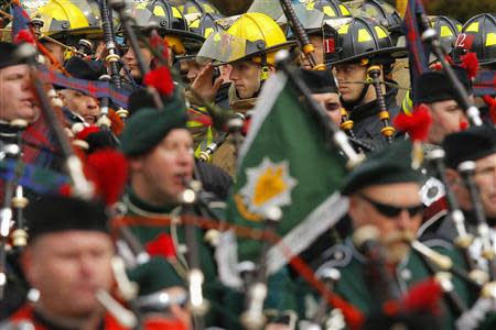 Firefighters salute and bagpipers march during the funeral procession of Boston Fire Department Lieutenant Edward Walsh to his funeral at Saint Patrick's Church in Watertown, Massachusetts April 2, 2014. REUTERS/Brian Snyder