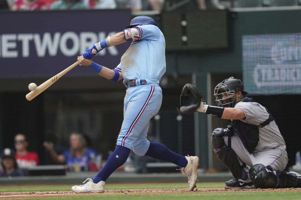 Texas Rangers' Josh Jung, left, hits a home run in front of Colorado Rockies catcher Austin Wynns (16) during the second inning of a baseball game in Arlington, Texas, Sunday, May 21, 2023. (AP Photo/LM Otero)