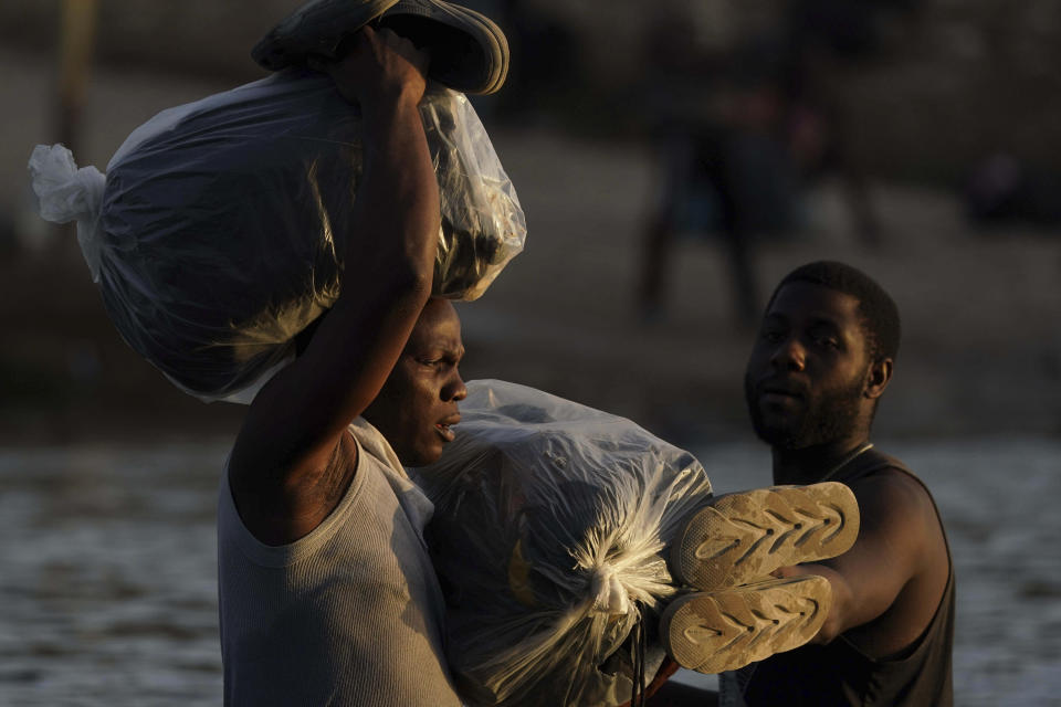 FILE - In the Sept. 22, 2021, file photo, migrants, many from Haiti, wade across the Rio Grande from Del Rio, Texas with their belongings to return to Ciudad Acuna, Mexico to avoid possible deportation from the U.S. The Border Patrol's treatment of Haitian migrants, they say, is just the latest in a long history of discriminatory U.S. policies and of indignities faced by Black people, sparking new anger among Haitian Americans, Black immigrant advocates and civil rights leaders.(AP Photo/Fernando Llano, File)