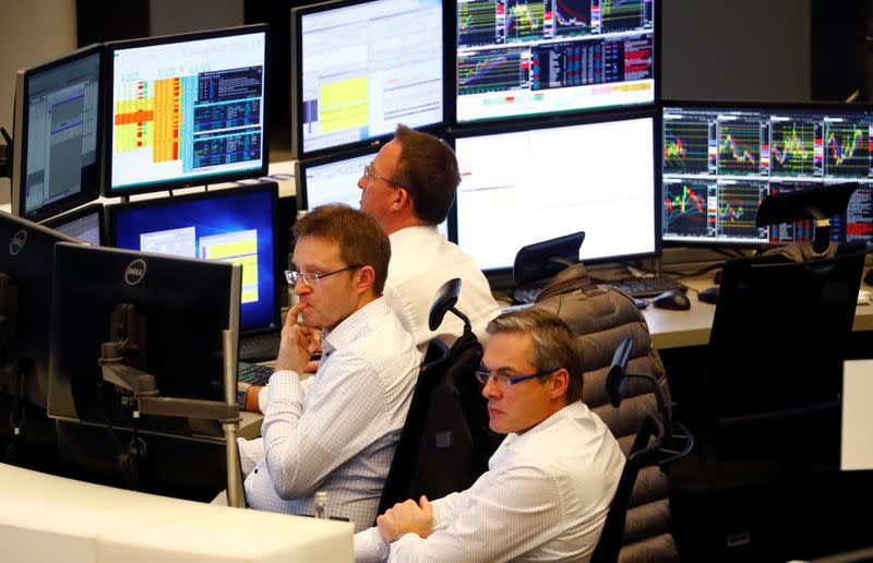 Share traders look at their screens during early afternoon trading at the stock exchange in Frankfurt