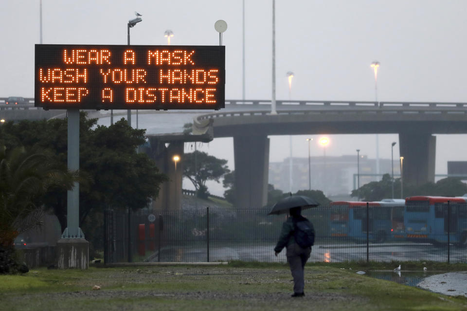 A man walks beneath a COVID-19 sign advising precautions people should take to prevent the spread of coronavirus in Cape Town, South Africa, Monday, June 29, 2020. South Africa’s reported coronavirus are surging. Its hospitals are now bracing for an onslaught of patients, setting up temporary wards and hoping advances in treatment will help the country’s health facilities from becoming overwhelmed. (AP Photo/Nardus Engelbrecht)