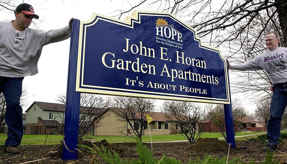 Mike Watt, left, and Jack Wodarski install a new John E. Horan Garden Apartments sign near East 12th Street and Franklin Avenue on Nov. 18, 2003. The sign, made by Howard Industries, shows the name change from Franklin Terrace Apartments.