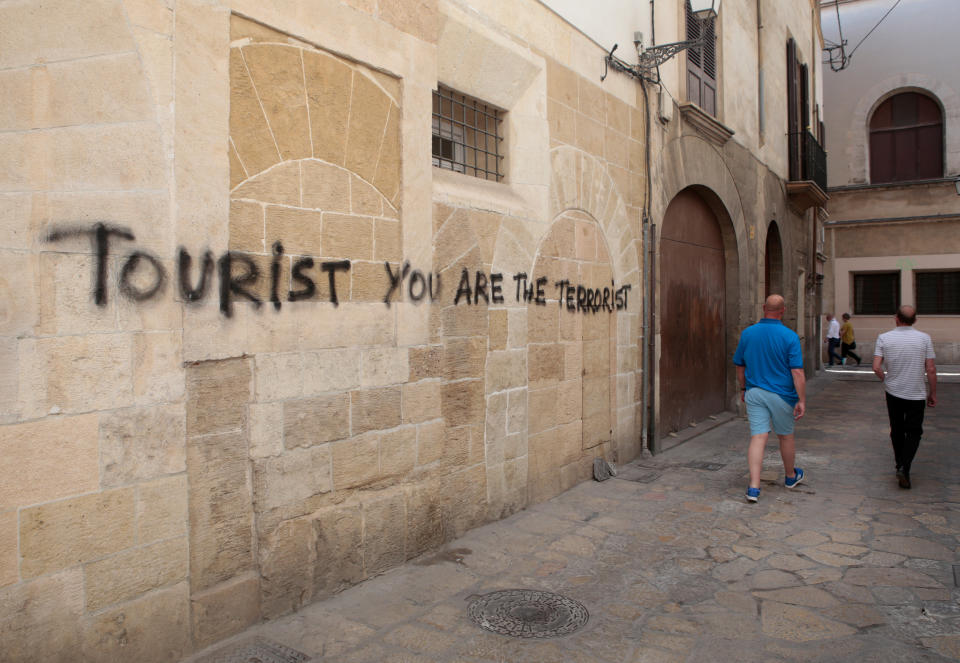 People walk past a graffiti in Palma de Mallorca, in the Spanish island of Mallorca, May 23, 2016. REUTERS/Enrique Calvo