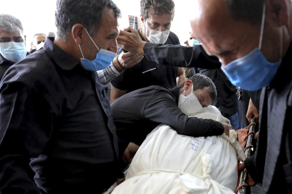 Relatives mourn over the body of a person who died from COVID-19, at the Behesht-e-Zahra cemetery just outside Tehran, Iran, Wednesday, April 21, 2021. After facing criticism for downplaying the virus last year, authorities have put partial lockdowns and other measures in place to try and slow the coronavirus’ spread, as Iran faces what looks like its worst wave of the coronavirus pandemic yet. (AP Photo/Ebrahim Noroozi)