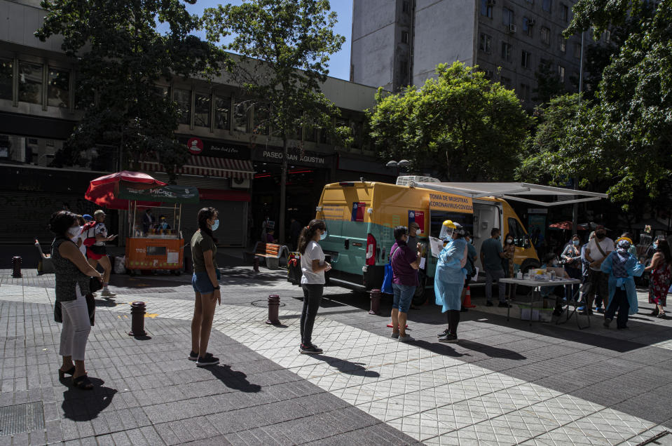 Un trabajador de la salud toma información de personas en fila para hacerse una prueba rápida de COVID-19 en una unidad móvil en el centro de Santiago, Chile, el lunes 11 de enero de 2021. (AP Foto/Esteban Felix)