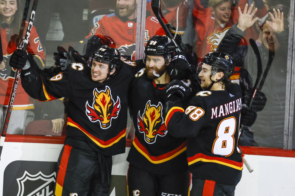 Calgary Flames forward Dillon Dube, center, celebrates his game-winning goal with teammates forward Jakob Pelletier, left, and forward Andrew Mangiapane in overtime of an NHL hockey game against the Columbus Blue Jackets in Calgary, Alberta, Monday, Jan. 23, 2023. (Jeff McIntosh/The Canadian Press via AP)