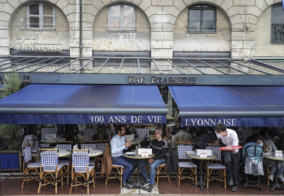 Customers sit at a cafe terrace in Lyon, central France, Wednesday, May, 19, 2021. It’s a grand day for the French. Cafe and restaurant terraces are reopening Wednesday after a pandemic shutdown of more than six months deprived people of what feels like the essence of life in France. (AP Photo/Laurent Cipriani)