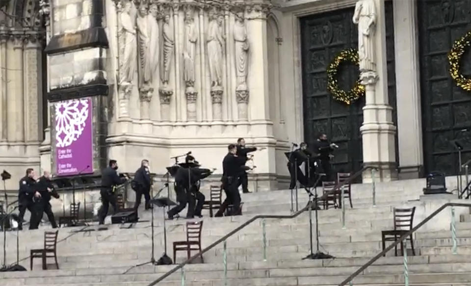 New York police officers move in on the scene of a shooting at the Cathedral Church of St. John the Divine, Sunday, Dec. 13, 2020, in New York. A man was shot by police after shots rang out at the end of a Christmas choral concert on the steps of the Manhattan cathedral Sunday afternoon. It's unclear if the gunman was killed or if any others were injured. The shooting happened just before 4 p.m. at the church which is the mother church of the Episcopal Diocese of New York and seat of its bishop. (AP Photo/Ted Shaffrey)