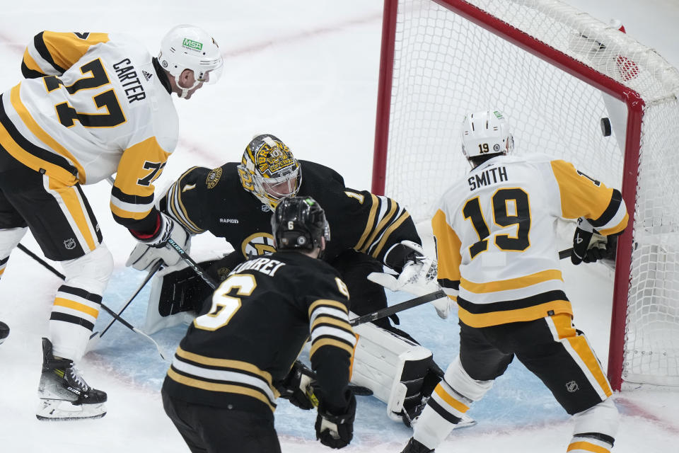 Pittsburgh Penguins center Jeff Carter (77) hits the puck into the net past Boston Bruins goaltender Jeremy Swayman (1), in front of Bruins defenseman Mason Lohrei (6) and Penguins right wing Reilly Smith (19) during the second period of an NHL hockey game Thursday, Jan. 4, 2024, in Boston. (AP Photo/Steven Senne)
