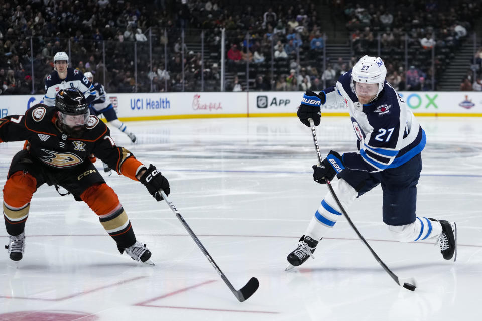 Winnipeg Jets left wing Nikolaj Ehlers, right, shoots past Anaheim Ducks defenseman Radko Gudas during the second period of an NHL hockey game Friday, Jan. 5, 2024, in Anaheim, Calif. (AP Photo/Ryan Sun)