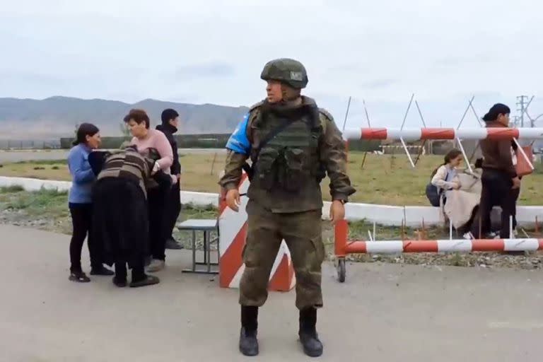 En este captura de video tomada de un material distribuido por el Ministerio de Defensa ruso el 21 de septiembre de 2023, un miembro de la fuerza de paz rusa hace guardia mientras civiles armenios ingresan a una base militar rusa cerca de Stepanakert en la región de Nagorno Karabaj.