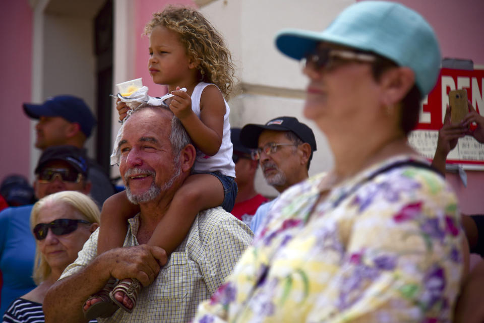 Musil Suarez carries his great granddaughter Alaina on his shoulders as they join a protest near La Fortaleza residence of Gov. Ricardo Rosselló against the governor in San Juan, Puerto Rico, Wednesday, July 17, 2019. Protesters are demanding Rosselló step down for his involvement in a private chat in which he used profanities to describe an ex-New York City councilwoman and a federal control board overseeing the island's finance. (AP Photo/Carlos Giusti)