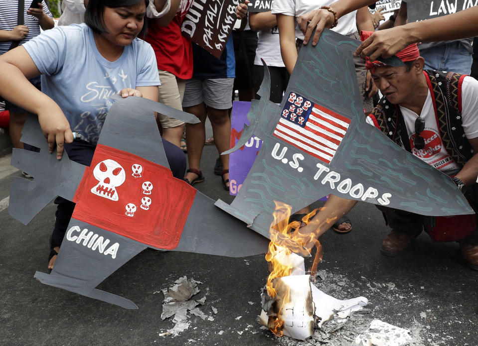 Protesters burn cardboard-cut jet fighters with mock U.S. and China flags as they hold a protest in front of the U.S. embassy in Manila, Philippines on Tuesday, March 5, 2019. The United States is more likely to be involved in a "shooting war" in the disputed South China Sea than the Philippines but the latter would be embroiled in such a conflict just the same because of its 1951 Mutual Defense Treaty with Washington, the Philippine defense chief said Tuesday. (AP Photo/Aaron Favila)