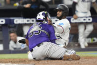 Miami Marlins' Bryan De La Cruz collides with Colorado Rockies catcher Elias Díaz (35) to score the game winning run during the 10 inning of a baseball game, Tuesday, April 30, 2024, in Miami. The Marlins defeated the Rockies 7-6. (AP Photo/Marta Lavandier)