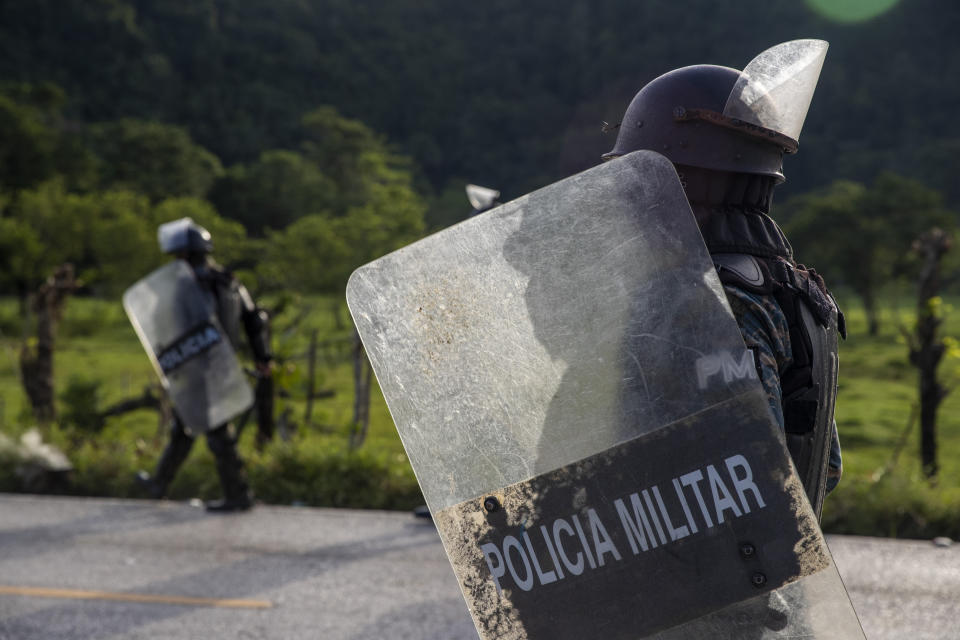 Security forces block Honduran migrants in San Luis Peten, Guatemala, Saturday, Oct. 3, 2020. Early Saturday, hundreds of migrants who had entered Guatemala this week without registering were being bused back to their country's border by authorities after running into a large roadblock. (AP Photo/Moises Castillo)