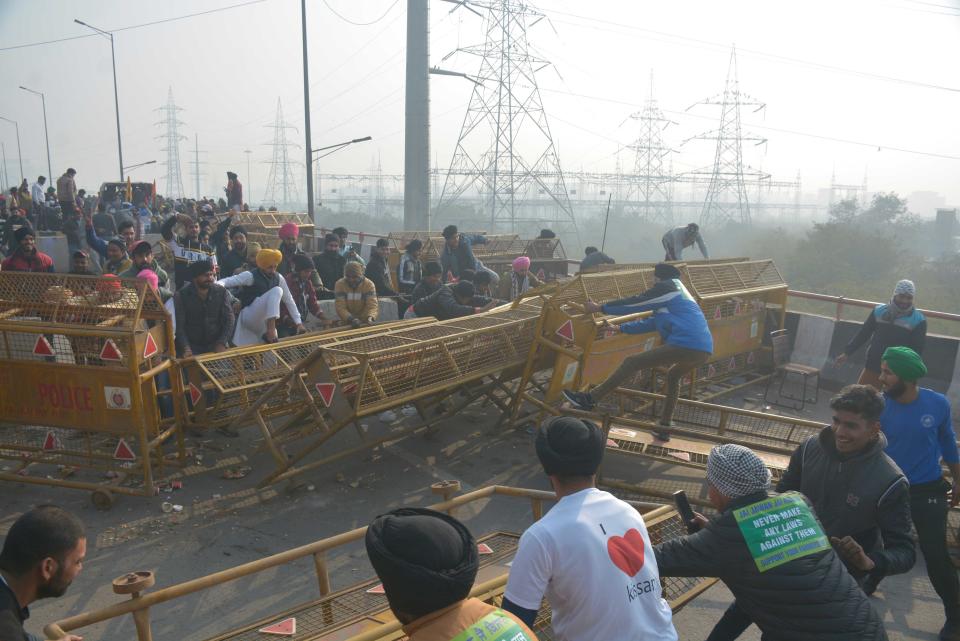 NEW DELHI, INDIA - JANUARY 26: Demonstrators breaking past police barricades while heading into the capital during a tractor rally on Republic Day, at Ghazipur on January 26, 2021 in New Delhi, India. Major scenes of chaos and mayhem at Delhi borders as groups of farmers allegedly broke barricades and police check posts and entered the national capital before permitted timings. Police used tear gas at Delhi's Mukarba Chowk to bring the groups under control. Clashes were also reported at ITO, Akshardham. Several rounds of talks between the government and protesting farmers have failed to resolve the impasse over the three farm laws. The kisan bodies, which have been protesting in the national capital for almost two months, demanding the repeal of three contentious farm laws have remained firm on their decision to hold a tractor rally on the occasion of Republic Day. (Photo by Sakib Ali/Hindustan Times via Getty Images)