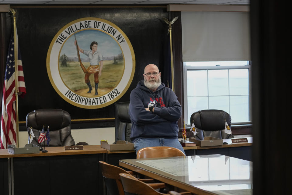 Ilion Mayor John Stephens poses for a picture in front of the seal of the village at the municipal building in Ilion, N.Y., Thursday, Feb. 1, 2024. The seal features Eliphalet Remington, the founder of Remington Arms Co., Inc. (AP Photo/Seth Wenig)