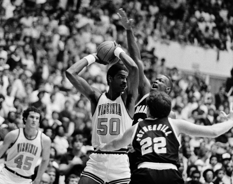 FILE - Virginia center Ralph Sampson (50) holds the ball away from Maryland defenders Mark Fothergill (22) and Adrian Branch, top right, during the first half of an Atlantic Coast Conference NCAA college basketball game in Charlottesville, Va., March 6, 1983. Sampson’s Cavaliers were among seven teams to sit at No. 1 in the AP men’s college basketball poll that year, one of only two seasons that has happened. (AP Photo/Steve Helber, File)