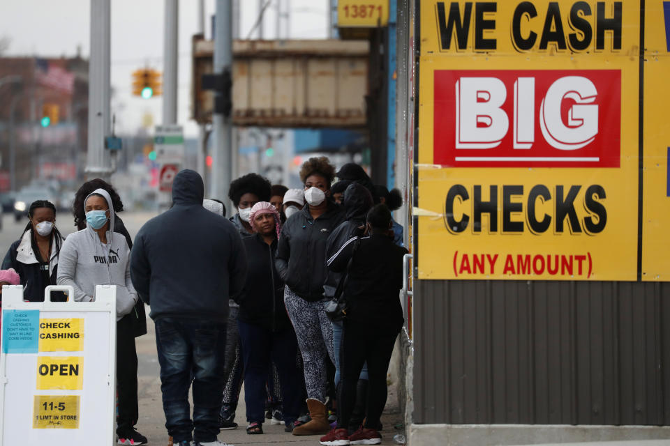 People wear face masks waiting outside a beauty salon and check cashing facility as the coronavirus disease (COVID-19) continues to spread, in the Highland Park section of Detroit, Michigan U.S., April 25, 2020.  REUTERS/Shannon Stapleton