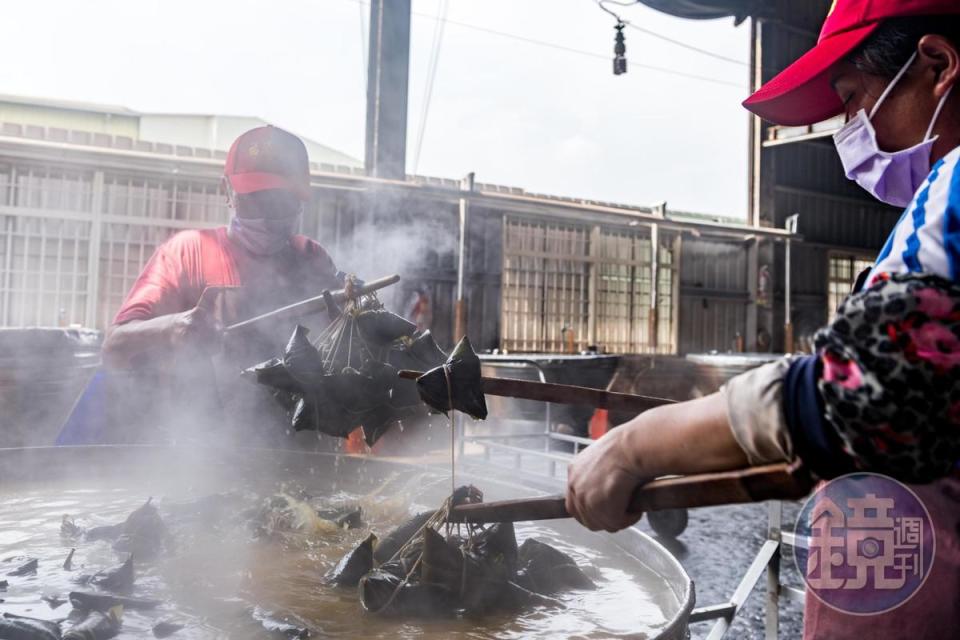 工作人員用巨筷挾起水煮好的熱騰騰粽子。