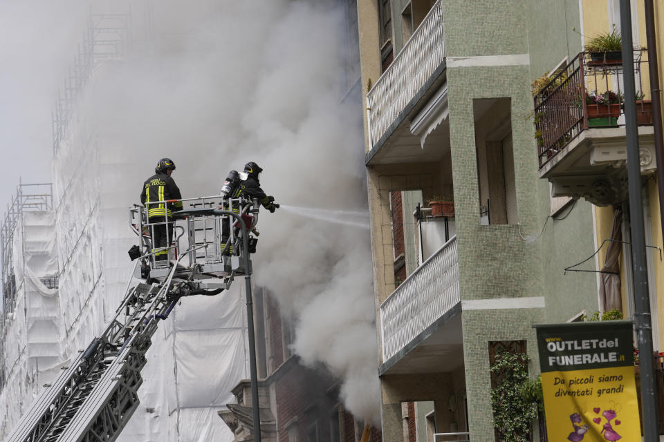 Firefighters work to extinguish a fire in a building after a van exploded in central Milan, northern Italy, Thursday, May 11, 2023. (AP Photo/Luca Bruno)