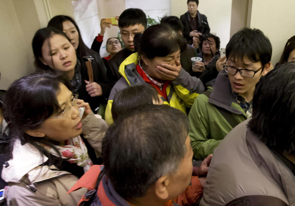 Una mujer rodeada por los reporteros de los medios de comunicación, cubre su boca mientras llega al hotel preparado para los familiares de los pasajeros a bordo del avión desaparecido. La imagen fue tomada en Beijing, China este sábado 8 de enero de 2014.(AP Photo/Andy Wong)